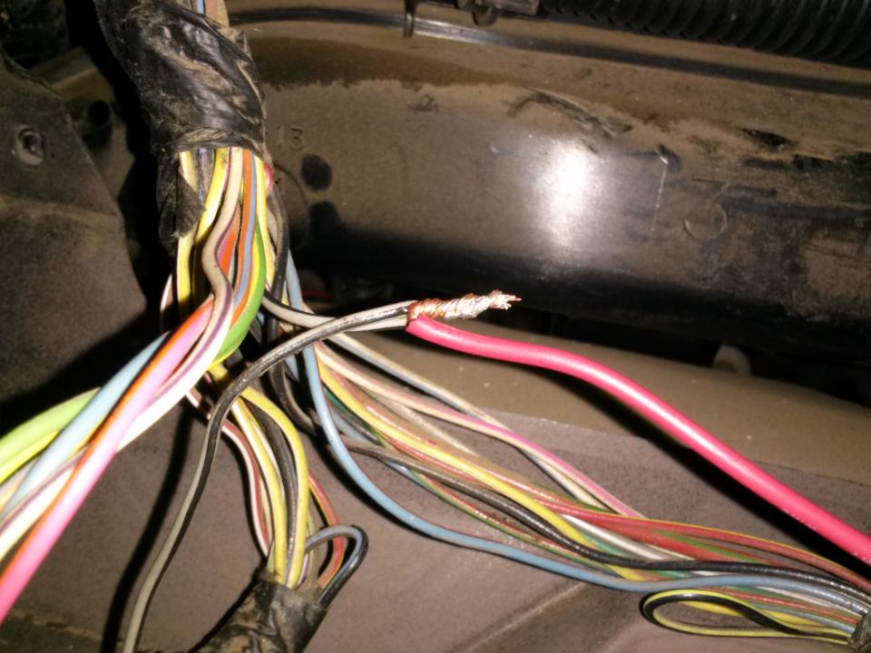 Close-up of a vehicle's wiring harness with several wires exposed and twisted together