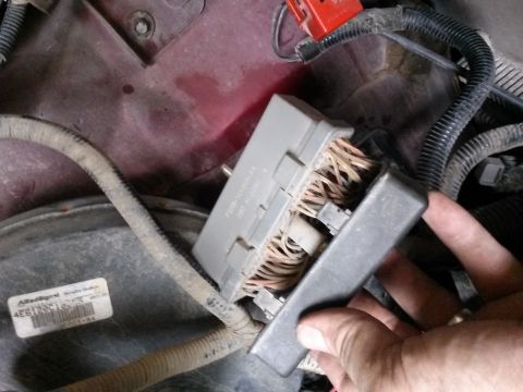 1996 Ford Bronco - Close-up of a vehicle's fuse box and wiring harness, with a hand obscuring part of the view.