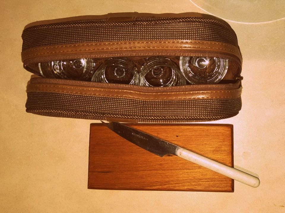 Four glass headlight bulbs in a brown zippered case next to a knife on a wooden block