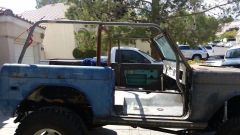 1979 Ford Bronco - This heavily modified blue Ford Bronco is missing its doors and roof, revealing its interior and roll cage structure.