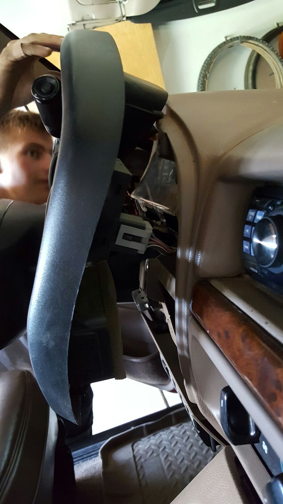 Interior view of a car's dashboard with exposed wiring and a person working on it