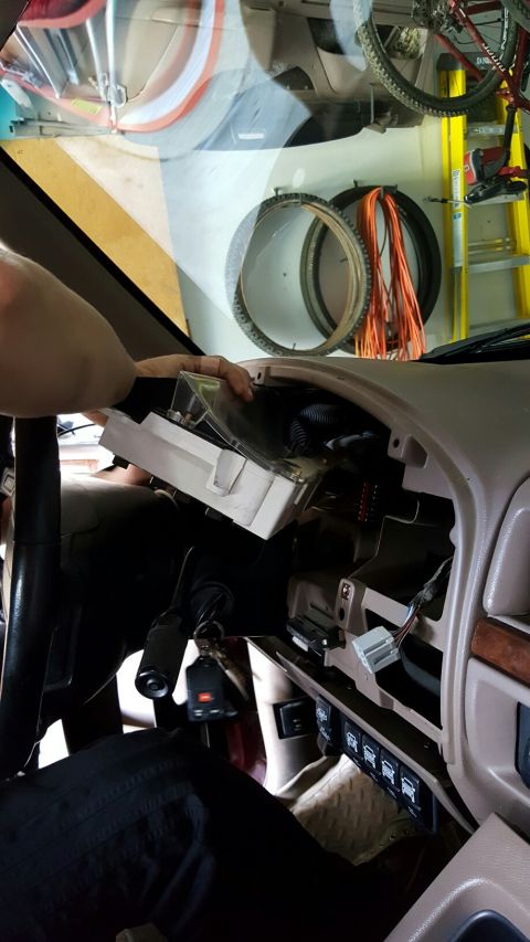 1996 Ford Bronco - The instrument cluster is being removed from the dashboard, revealing wiring underneath.