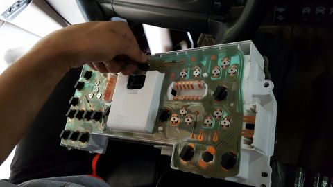 1996 Ford Bronco - A hand disconnects a connector from a vehicle's dashboard instrument cluster circuit board.
