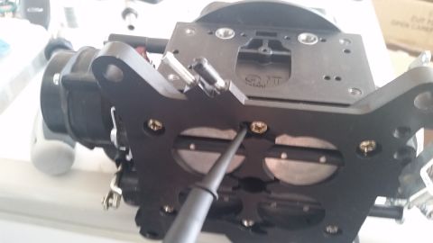 1981 Ford Bronco - A close-up view of a carburetor, showing its internal components and a tool being used for adjustment.