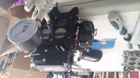1981 Ford Bronco - A black carburetor is shown with a fuel pressure gauge attached, suggesting it is part of an engine assembly.