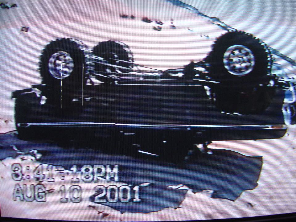 Dark SUV flipped upside down on its roof, wheels up, dated Aug 10 2001