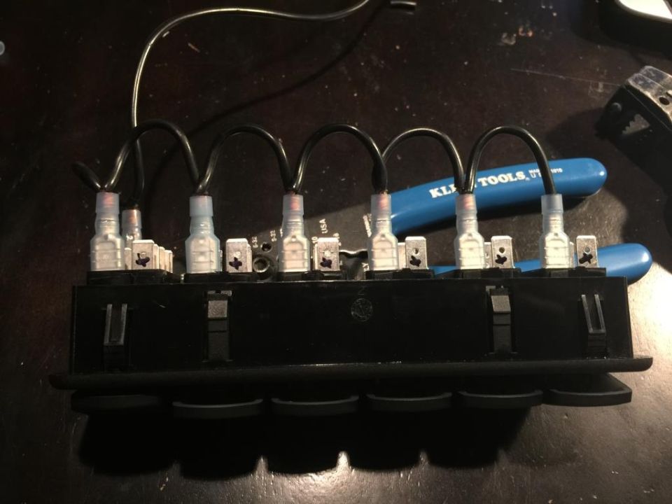 Wiring harness connected to a block of rocker switches, with a blue KLI TOOLS plier in the background