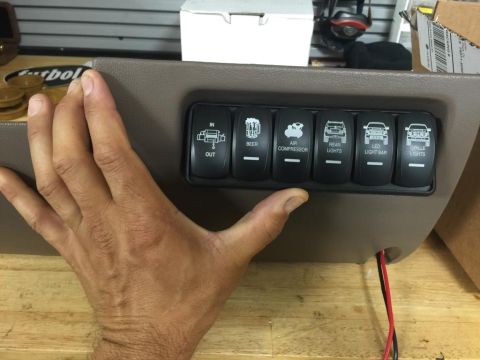 1996 Ford Bronco - A hand holds a custom rocker switch panel with various icons for vehicle accessories.