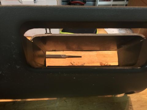 1996 Ford Bronco - A file rests on a wooden block inside a dark gray interior panel opening.