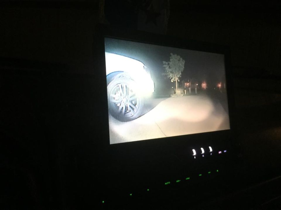 Backup camera view of a car tire and road at night, with headlights illuminating the scene
