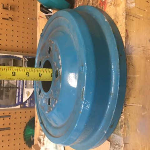 1930 Ford Coupe - A blue painted wheel drum is measured with a tape measure. The drum has multiple bolt holes.