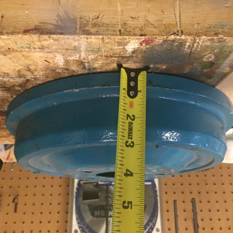 1930 Ford Coupe - A blue painted metal part is measured with a tape measure. The part appears to be a hubcap or similar automotive component.