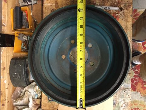 1930 Ford Coupe - A blue brake drum is measured with a yellow tape measure on a wooden surface.