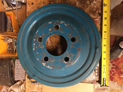 1930 Ford Coupe - A blue metal wheel with five bolt holes and visible rust is shown next to a measuring tape.