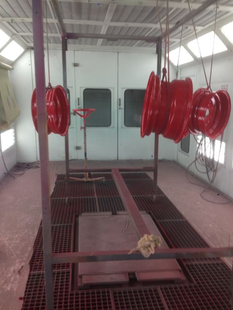 1964 Ford Fairlane - Several red wheels are suspended and drying inside a professional paint booth.