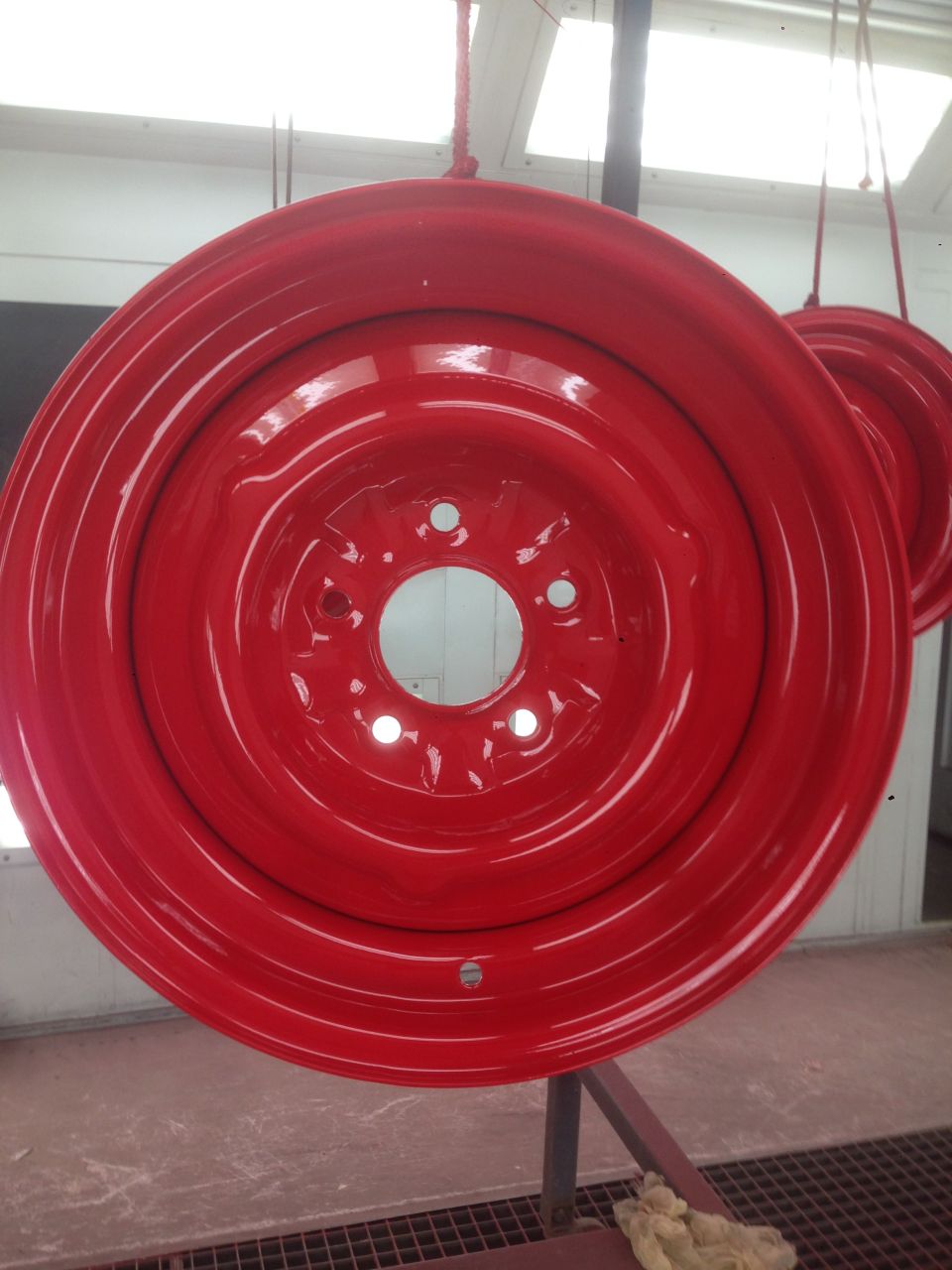 red painted steel wheel rim hanging, another rim visible behind it
