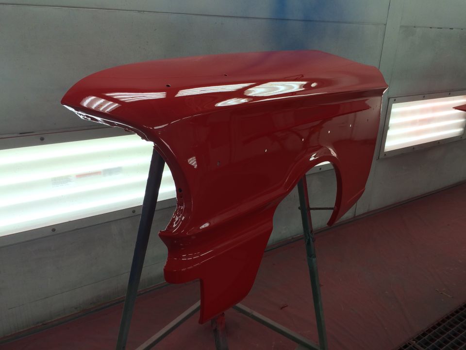 Red car fender on a stand in a paint booth