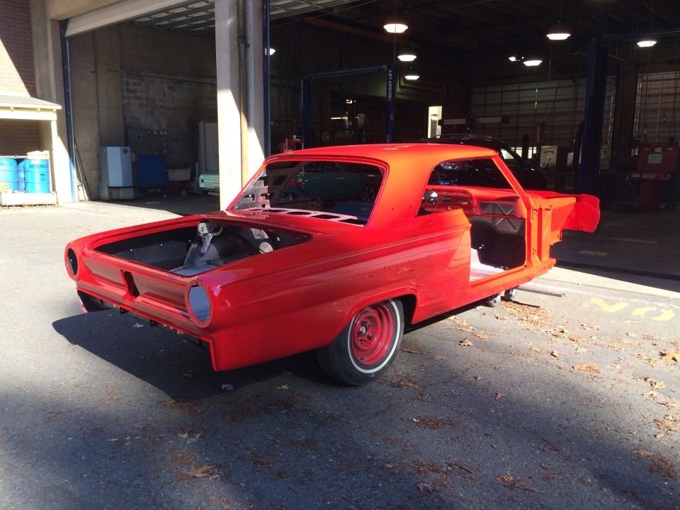 Red 1964 Ford Fairlane body in a garage, stripped down for restoration. Hood and doors are open