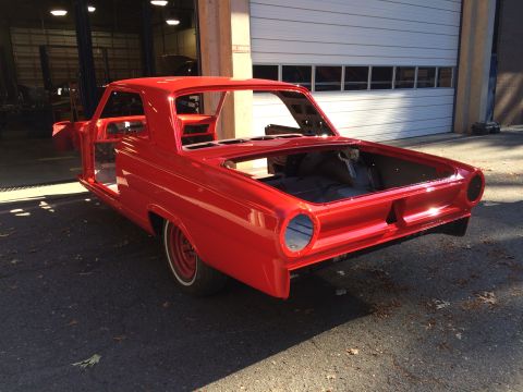 1964 Ford Fairlane - A bright red 1964 Ford Fairlane coupe body shell sits outside a garage, awaiting restoration.