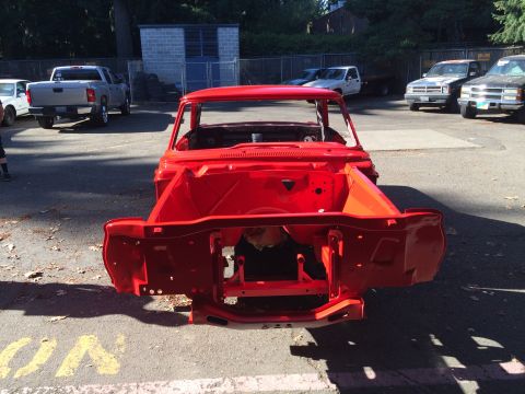 1964 Ford Fairlane - A red car body shell is shown from the front, with other vehicles parked in the background.
