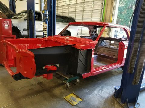 1964 Ford Fairlane - The body of a red 1964 Ford Fairlane is shown on a lift, stripped down for restoration work.