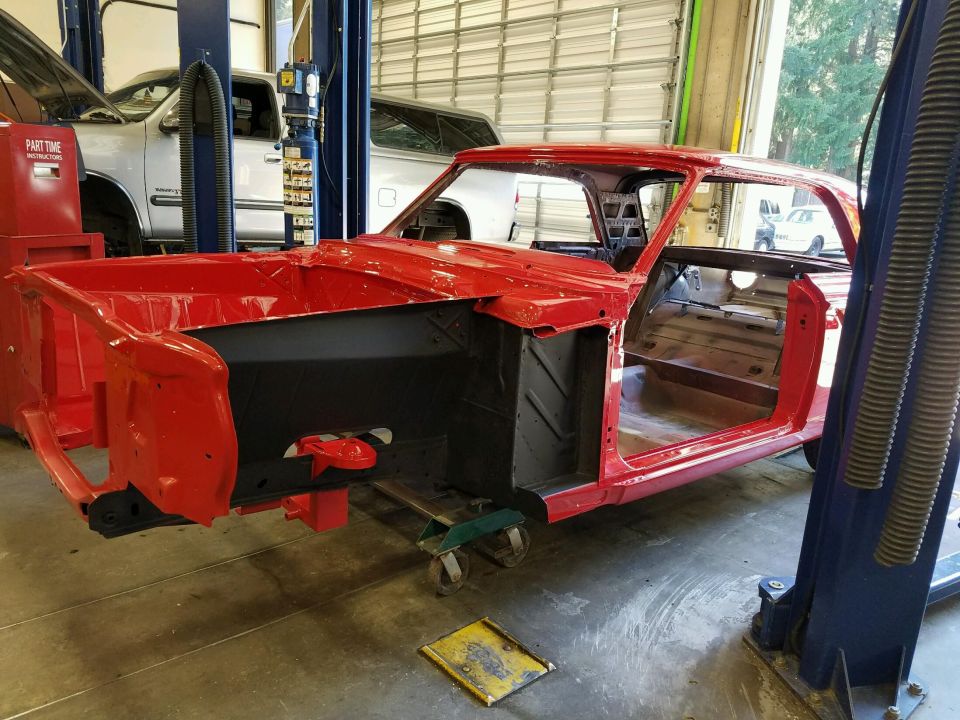 Red 1964 Ford Fairlane body on lift, stripped for restoration