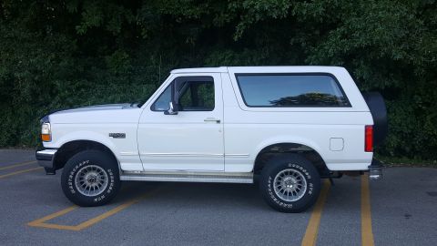 1995 Ford Bronco - This white Ford Bronco is parked on asphalt with yellow lines visible on the ground.