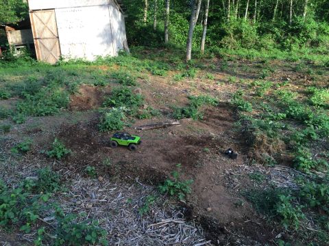 1989 Ford Bronco - Two remote control vehicles are visible on a dirt path in a wooded area next to a shed.