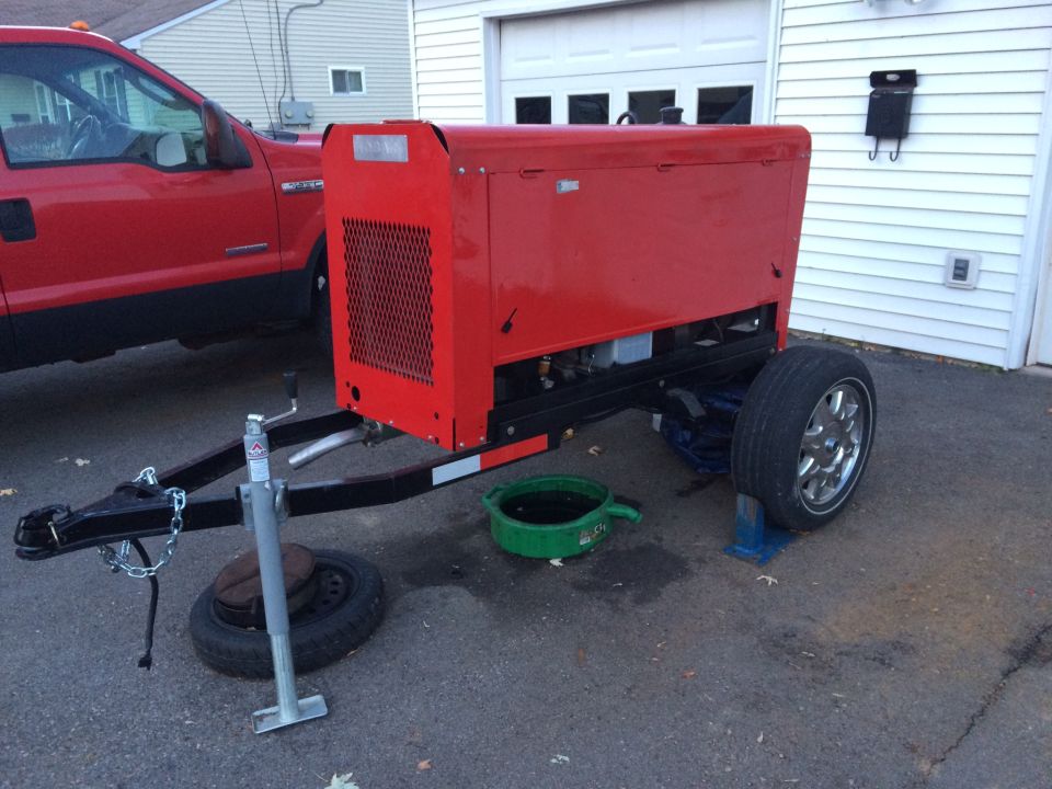 Red 2006 Ford F-250 pickup truck parked next to a red welding generator on a trailer