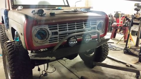 1979 Ford Bronco - Front view of a 1979 Ford Bronco in a workshop, showing its grille and custom bumper.