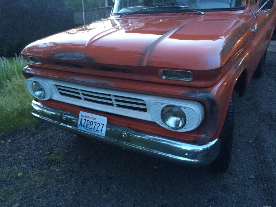 Orange pickup truck front end with white grille and Washington license plate AZR8727