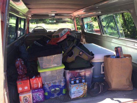 1962 Chevrolet Suburban - Vehicle interior packed with coolers, drinks, and bags, including a toy SUV on the dashboard.