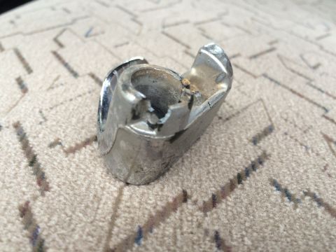 1962 Chevrolet Suburban - A close-up view of a damaged chrome part resting on a carpeted surface.