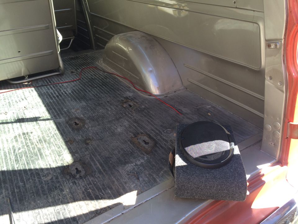 Interior cargo area of a van or truck, showing ribbed floor, wheel well, and a speaker box