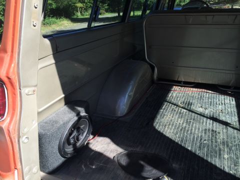 1962 Chevrolet Suburban - The rear interior of a vintage station wagon is visible, a subwoofer and a worn floor mat.