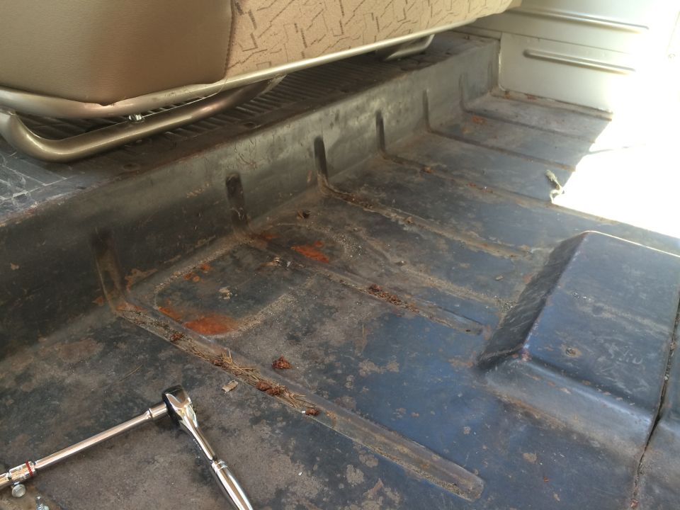 Interior floor of a vehicle with a socket wrench and worn seat fabric