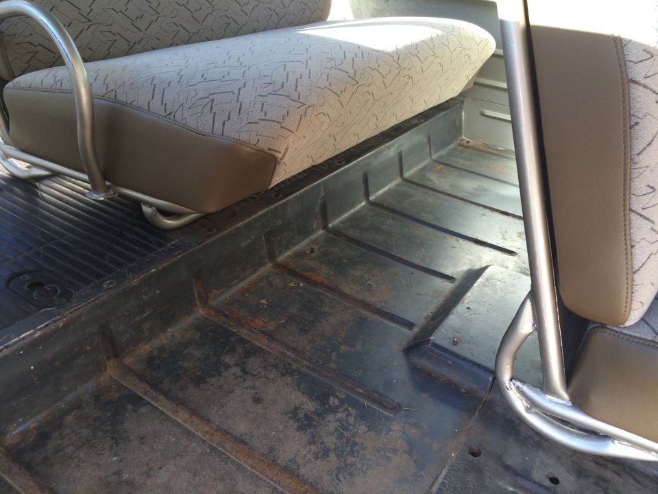 Interior floor of a vehicle showing wear and a portion of a seat with patterned upholstery