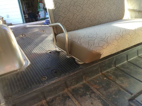 1962 Chevrolet Suburban - The interior of a vehicle shows a bench seat with patterned upholstery and a ribbed floor, possibly in a garage setting.