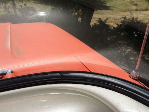1962 Chevrolet Suburban - The hood and windshield frame of an orange vehicle are visible from a high angle.