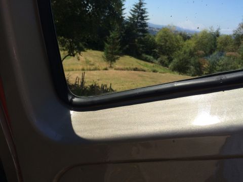 1962 Chevrolet Suburban - View from inside a vehicle shows a rural landscape with rolling hills and trees under a clear blue sky.