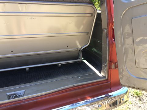 1962 Chevrolet Suburban - Interior view of a vehicle's rear seating area and floor, showing metallic silver upholstery and orange exterior paint.