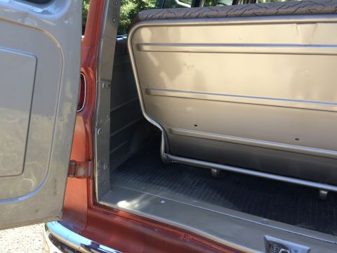 1962 Chevrolet Suburban - The interior of a 1962 Chevrolet Suburban shows tan upholstery and the vehicle's orange exterior paint.