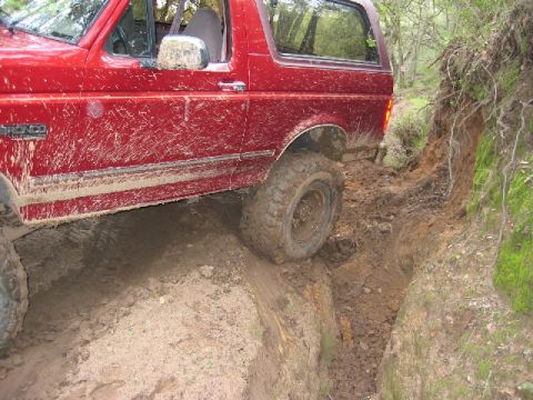 1989 Ford Bronco - This 1989 Ford Bronco is navigating a challenging muddy terrain, with its tires deep in the dirt.