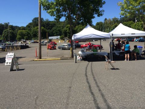 1962 Chevrolet Suburban - A car show scene with multiple vehicles, tents, and a sign indicating the entrance.