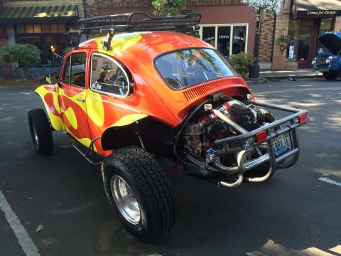 1962 Chevrolet Suburban - A heavily modified Volkswagen Beetle with a vibrant flame paint job and off-road modifications is parked on a street.