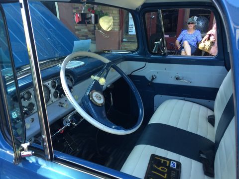 1962 Chevrolet Suburban - The interior of a classic truck features a two-tone blue and white color scheme with a large steering wheel and a woman visible through the…