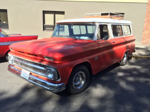 1962 Chevrolet Suburban - A red and white 1962 Chevrolet Suburban, a roof rack and a classic grille, is parked outdoors.