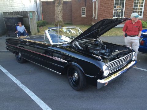 1962 Chevrolet Suburban - A black convertible is displayed with its hood up, revealing the engine compartment.