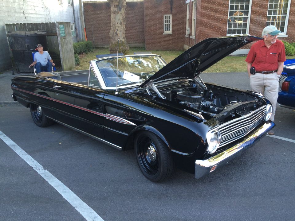 Black convertible with hood open, showing the engine. A man stands next to it