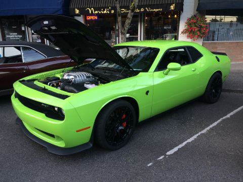 1962 Chevrolet Suburban - A lime green Dodge Challenger SRT Hellcat is displayed with its hood open, revealing the engine, at a car show.